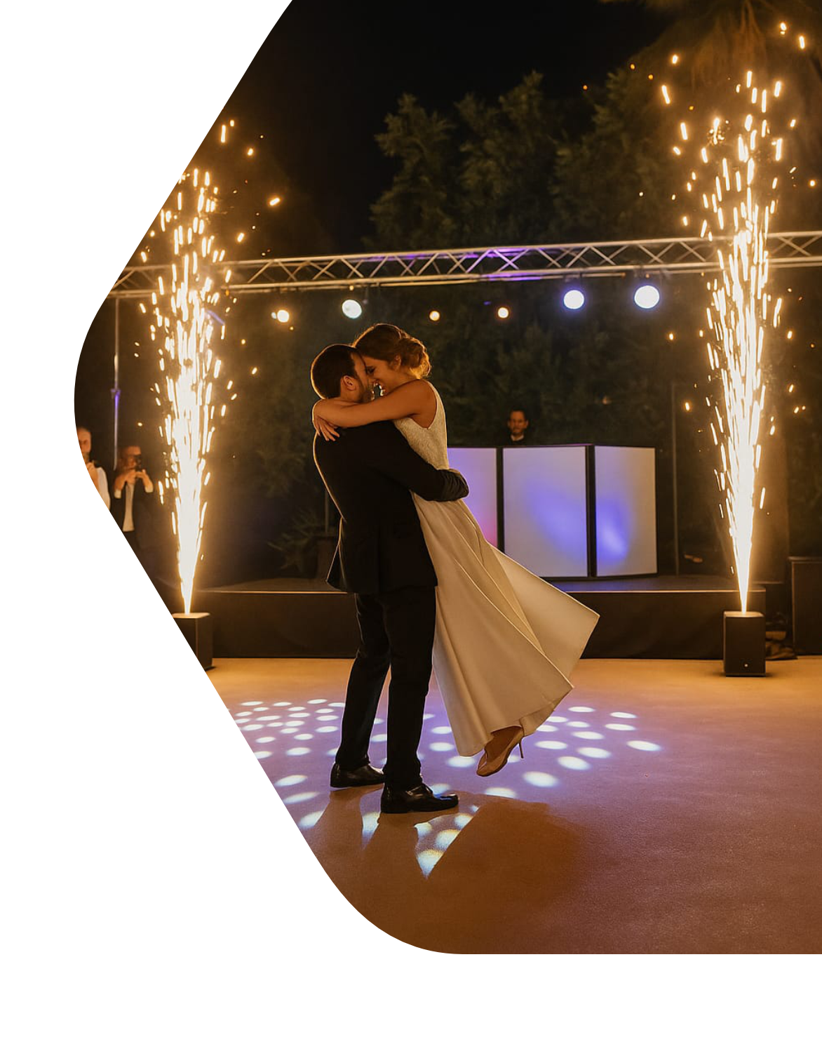 Baile nupcial con escenario y pirotecnia fría de fondo